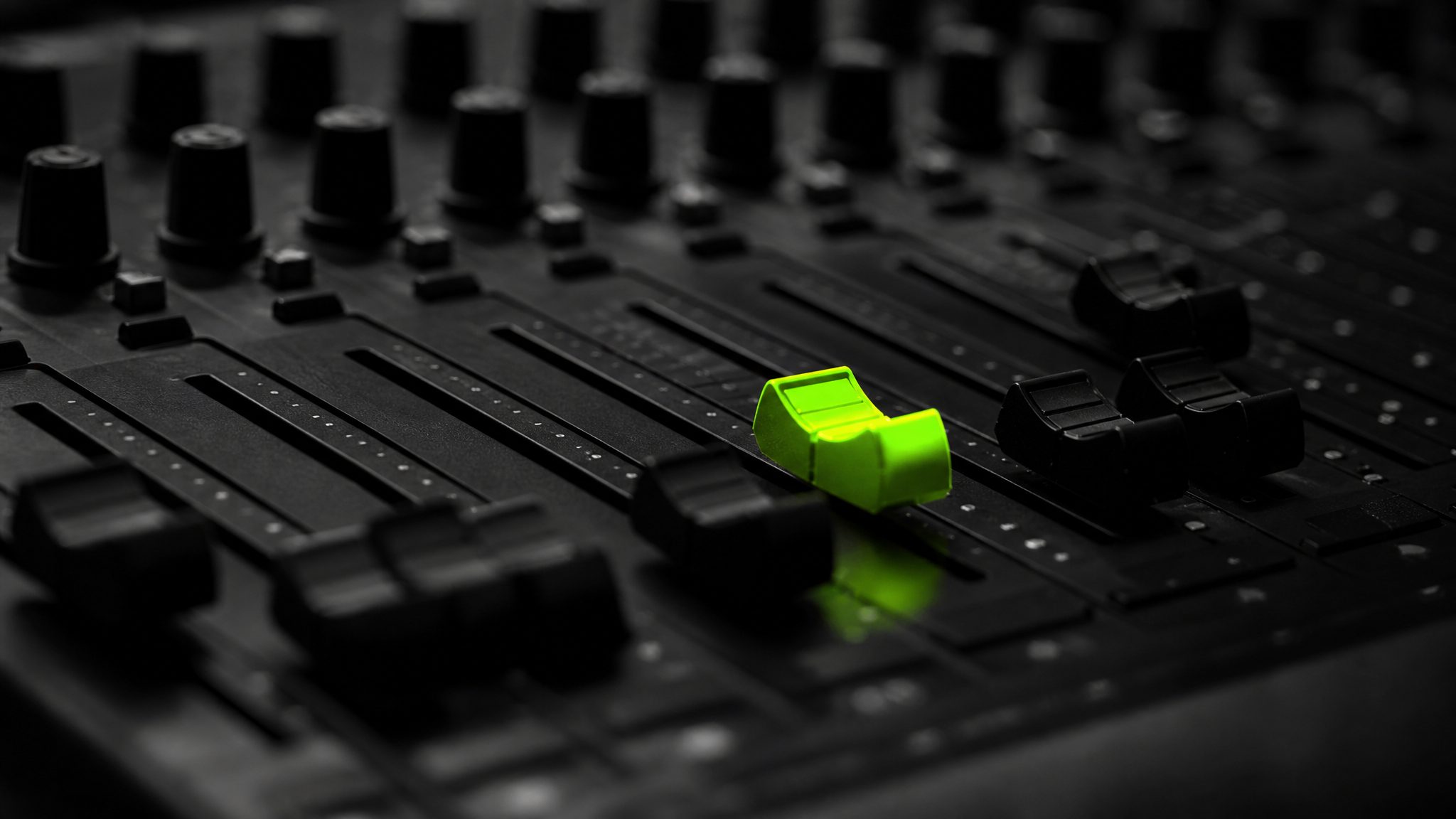 Black mixing panel with one acid-green fader glowing